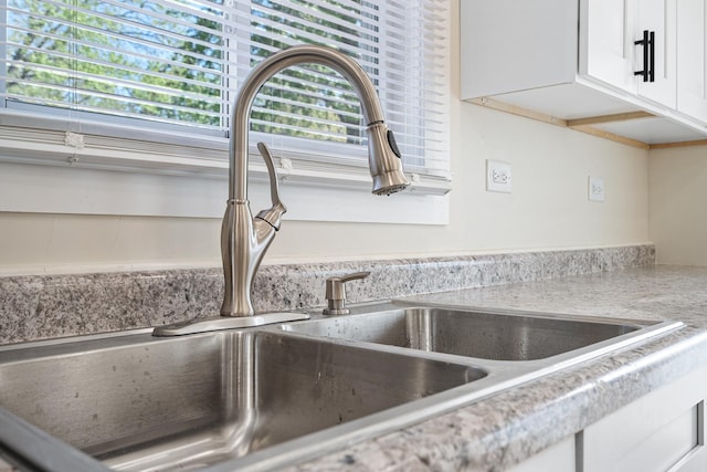 kitchen view of a sink, white cabinets, and light countertops