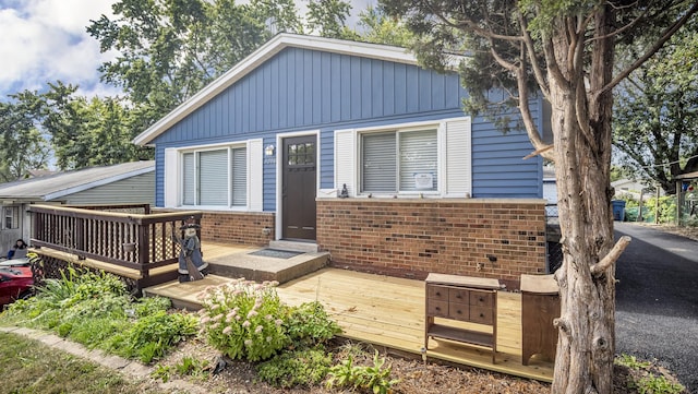 view of front of house with a deck, brick siding, and board and batten siding