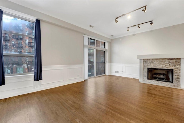 1910 S State St Unit 231, Chicago, IL 60616 - unfurnished living room with a stone fireplace, wainscoting, wood finished floors, a decorative wall, and track lighting