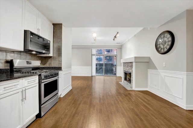 1910 S State St Unit 231, Chicago, IL 60616 - kitchen featuring appliances with stainless steel finishes, wood finished floors, a stone fireplace, dark stone countertops, and a decorative wall