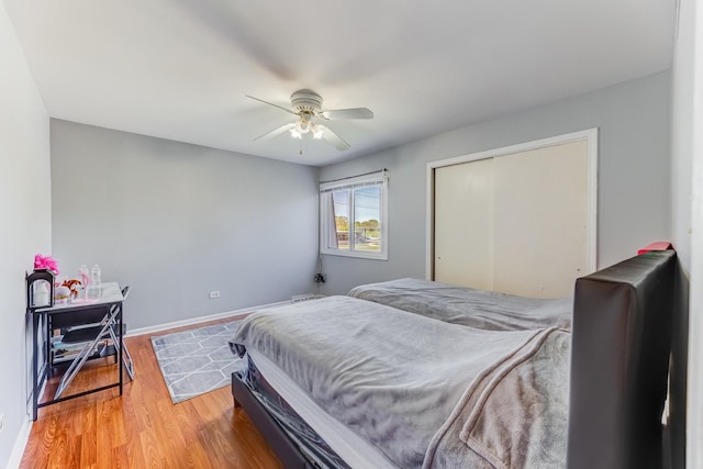 bedroom with wood finished floors, ceiling fan, baseboards, and a closet