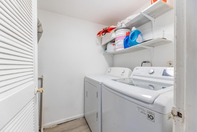 clothes washing area with separate washer and dryer, light wood finished floors, and baseboards
