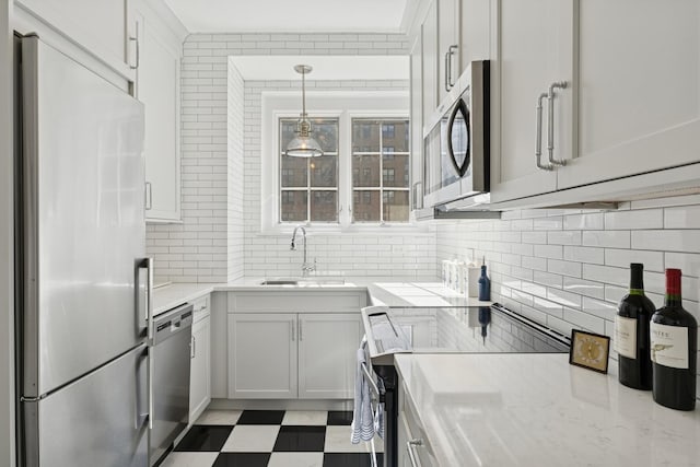 kitchen with stainless steel appliances, a sink, decorative backsplash, tile patterned floors, and hanging light fixtures