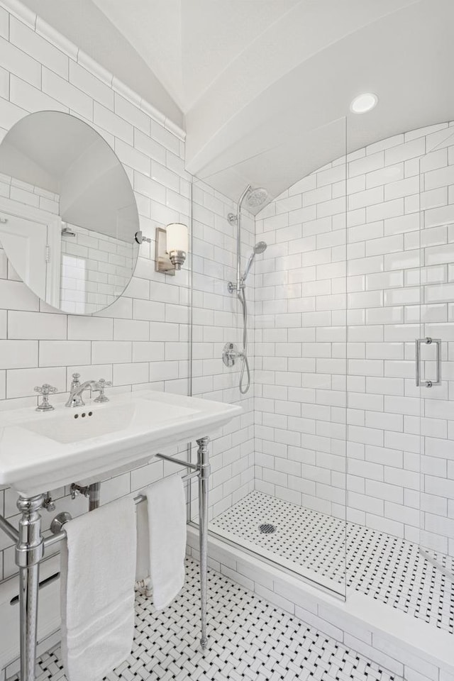 bathroom with a stall shower, tile walls, and vaulted ceiling