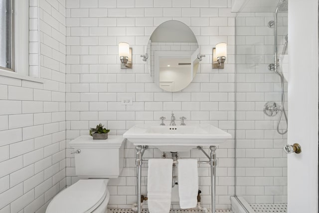 bathroom featuring tile walls, a shower stall, toilet, and a sink