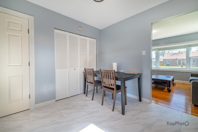 dining room with marble look tiles and baseboards