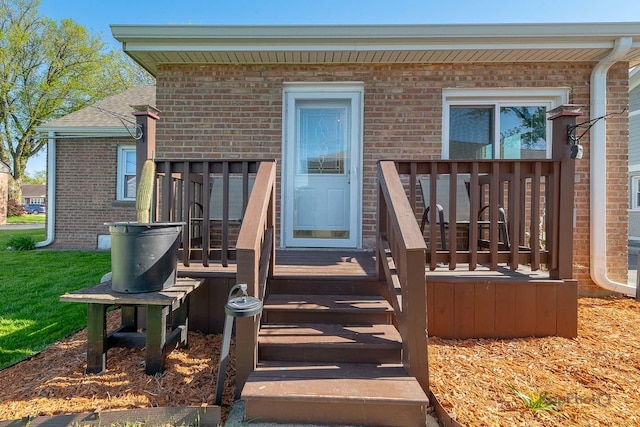 property entrance with brick siding and a wooden deck