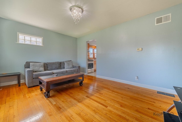 living room with a chandelier, baseboards, light wood-style floors, and plenty of natural light