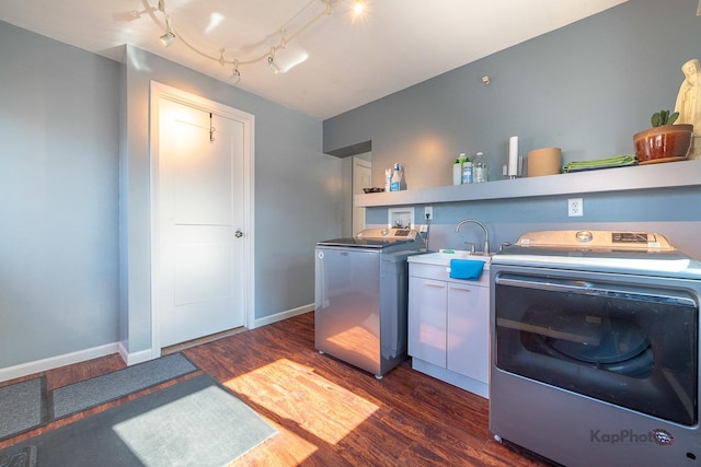 kitchen featuring washing machine and clothes dryer, dark wood-style flooring, a sink, and baseboards