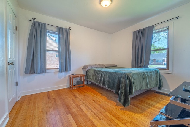 bedroom featuring light wood-type flooring, multiple windows, and baseboards