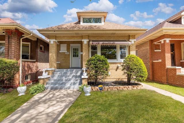 8109 S Marquette Ave, Chicago, IL 60617 - view of front of house with a front yard, brick siding, a shingled roof, and a porch