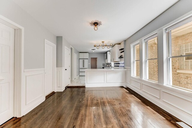 8109 S Marquette Ave, Chicago, IL 60617 - unfurnished dining area featuring a decorative wall, dark wood-style flooring, and a wainscoted wall