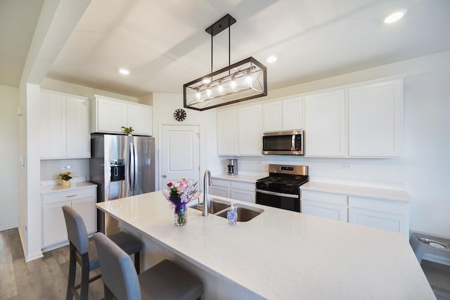 kitchen with appliances with stainless steel finishes, a sink, a kitchen breakfast bar, white cabinetry, and recessed lighting