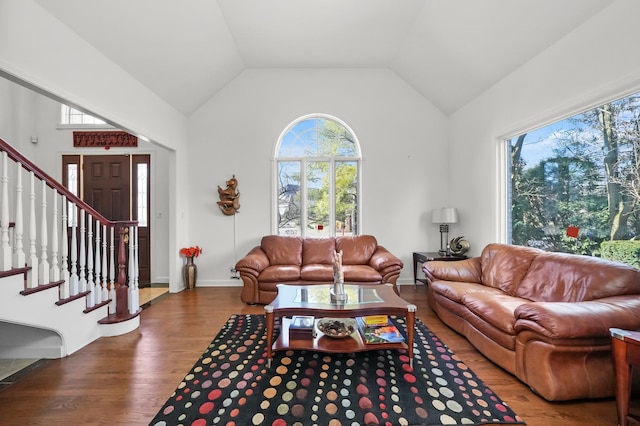 living area with wood finished floors, plenty of natural light, stairs, and vaulted ceiling