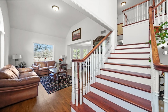 staircase featuring wood finished floors and high vaulted ceiling