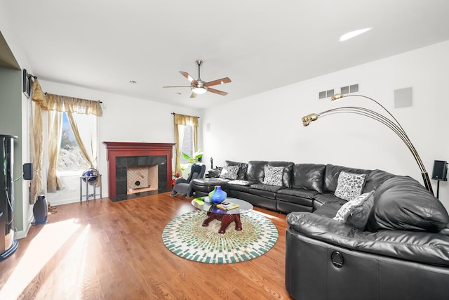 living room with wood finished floors, a tile fireplace, and ceiling fan