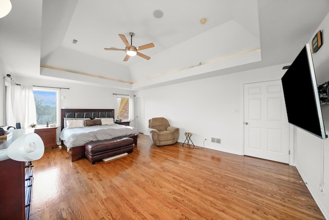 bedroom featuring a tray ceiling, light wood-style floors, and a ceiling fan