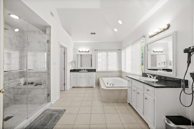 full bath featuring a garden tub, a shower stall, tile patterned flooring, two vanities, and vaulted ceiling