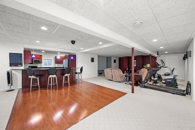 workout room with a paneled ceiling, bar area, recessed lighting, and baseboards
