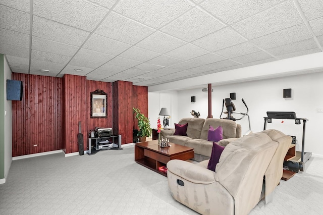 carpeted living area featuring baseboards and wood walls