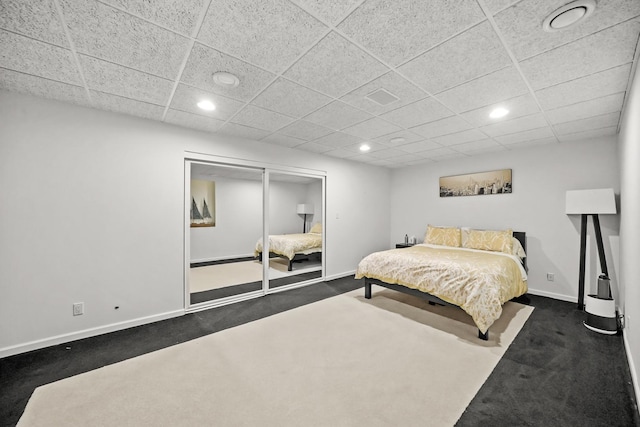 bedroom with recessed lighting, baseboards, dark carpet, and a paneled ceiling