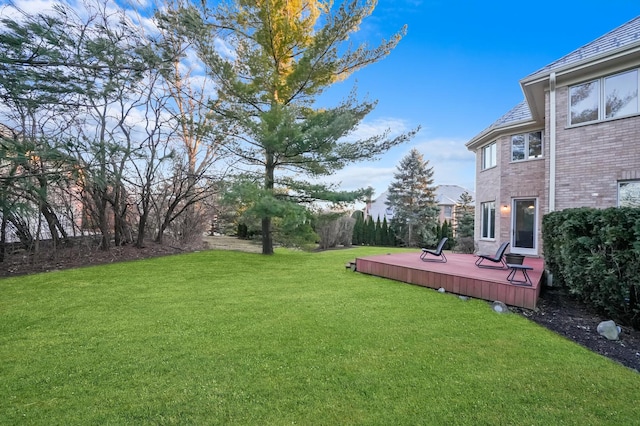 view of green lawn featuring a deck