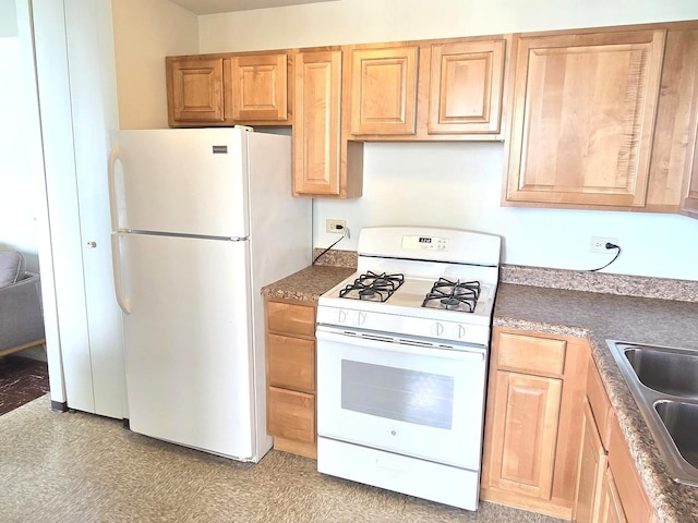kitchen featuring white appliances, a sink, light flooring, and light brown cabinets