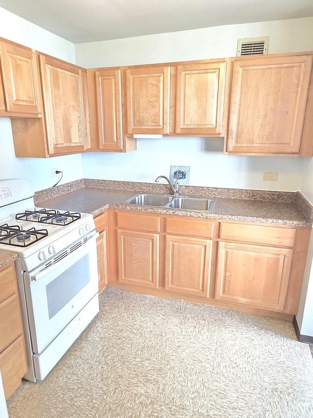 kitchen with white range with gas cooktop, a sink, and light brown cabinetry