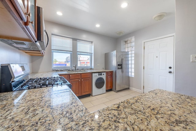 4006 W Nelson St Unit 6A, Chicago, IL 60641 - kitchen featuring appliances with stainless steel finishes, washer / dryer, brown cabinetry, a sink, and light stone countertops