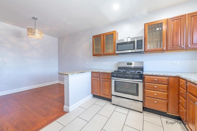 4006 W Nelson St Unit 6A, Chicago, IL 60641 - kitchen featuring stainless steel appliances, brown cabinets, a peninsula, light stone countertops, and glass insert cabinets