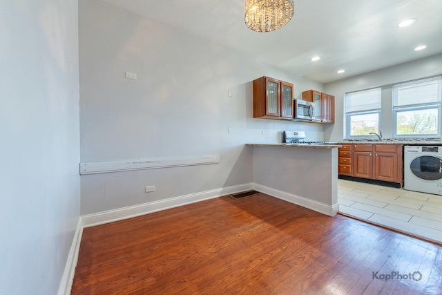 4006 W Nelson St Unit 6A, Chicago, IL 60641 - kitchen featuring washer / clothes dryer, stainless steel microwave, stove, brown cabinets, and light wood-type flooring