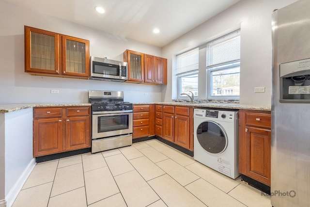 4006 W Nelson St Unit 6A, Chicago, IL 60641 - kitchen featuring appliances with stainless steel finishes, washer / clothes dryer, brown cabinets, light stone countertops, and glass insert cabinets