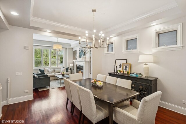 dining room with dark wood-style floors, baseboards, ornamental molding, a tray ceiling, and a chandelier