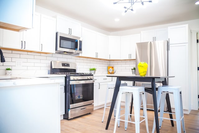 118 W 118th St, Chicago, IL 60628 - kitchen featuring appliances with stainless steel finishes, light countertops, white cabinets, light wood-style floors, and recessed lighting