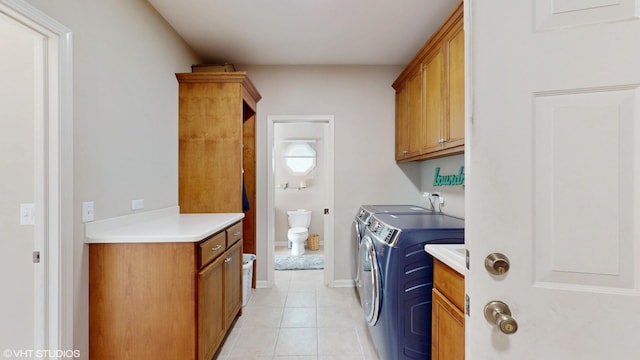 clothes washing area featuring cabinet space, washing machine and dryer, light tile patterned flooring, and baseboards