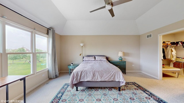 carpeted bedroom featuring lofted ceiling, multiple windows, baseboards, a walk in closet, and ceiling fan