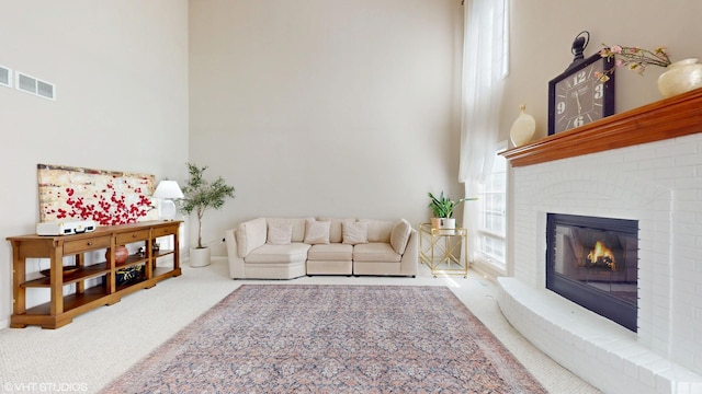 living room featuring carpet floors, a high ceiling, and a fireplace
