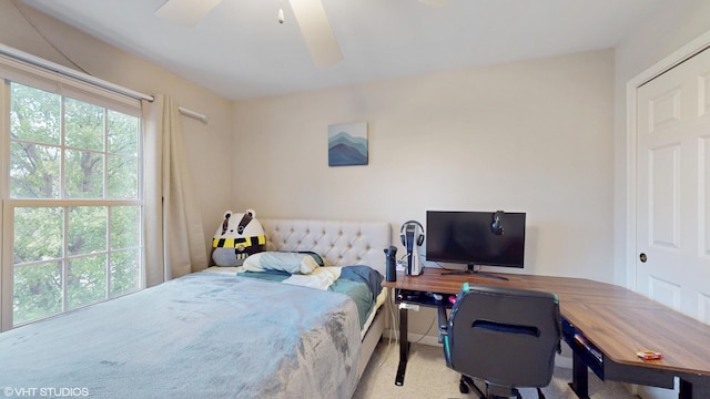 carpeted bedroom with an office area and ceiling fan