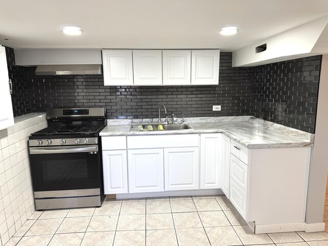 5343 W Warwick Ave, Chicago, IL 60641 - kitchen featuring gas stove, a sink, white cabinetry, light tile patterned floors, and wall chimney exhaust hood