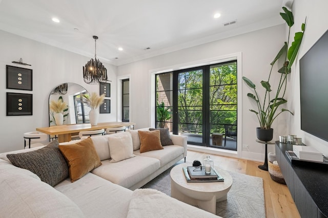 living area with a chandelier, recessed lighting, light wood finished floors, ornamental molding, and baseboards