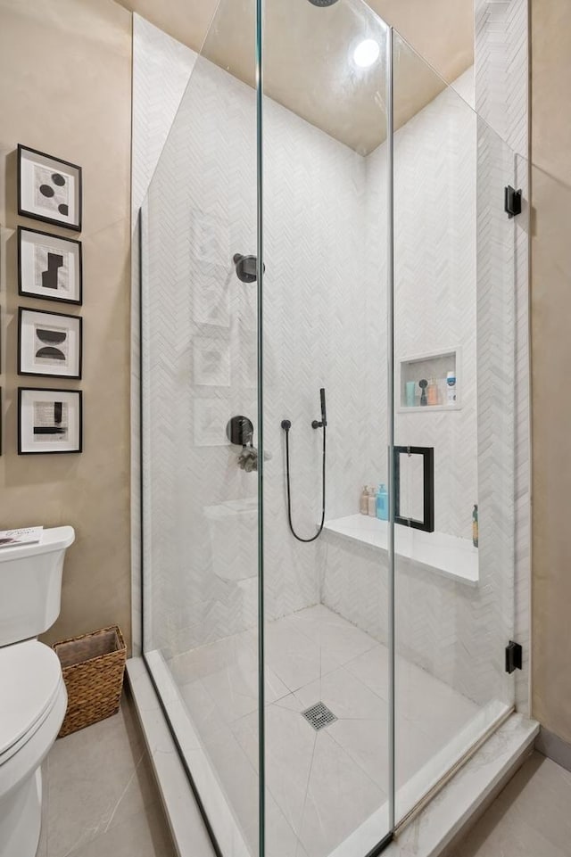 bathroom with toilet, a shower stall, and tile patterned floors