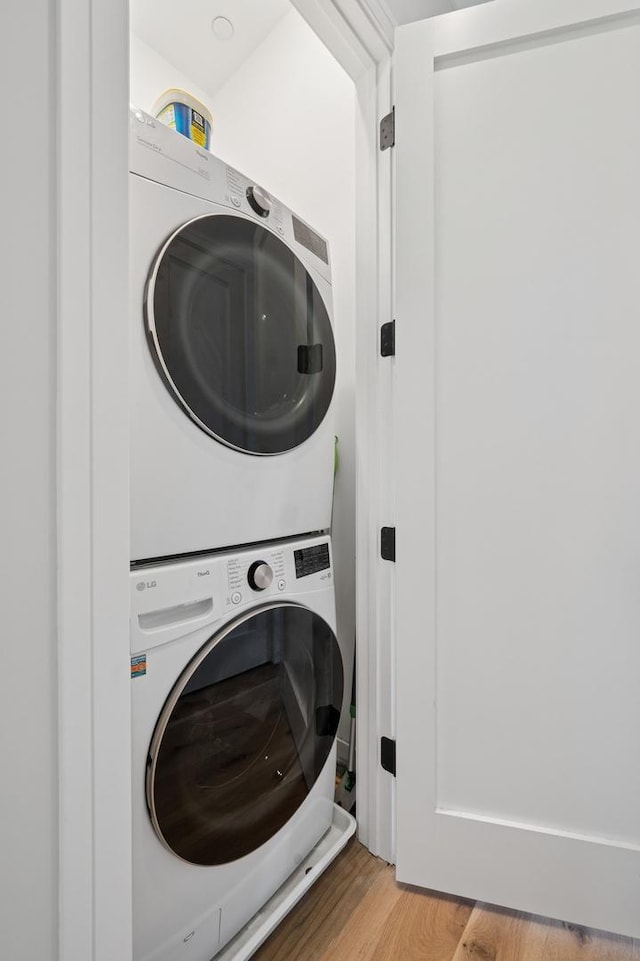 clothes washing area featuring stacked washer / drying machine and light wood-style floors