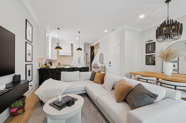living room featuring stairway, light wood-type flooring, crown molding, recessed lighting, and a chandelier