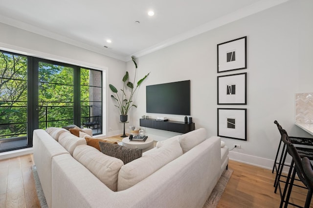 living room with wood finished floors, baseboards, ornamental molding, and recessed lighting