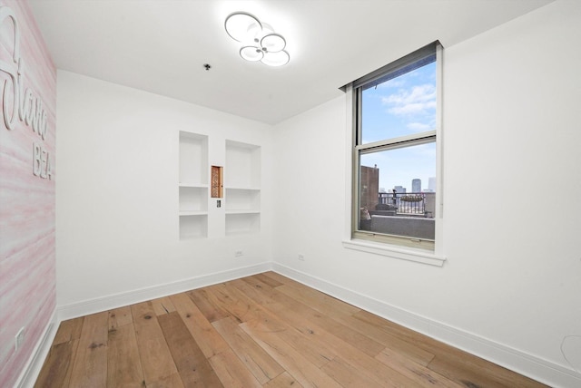 6 S Laflin St Unit 913, Chicago, IL 60607 - empty room with wood-type flooring, built in shelves, baseboards, and a pendent fire sprinkler