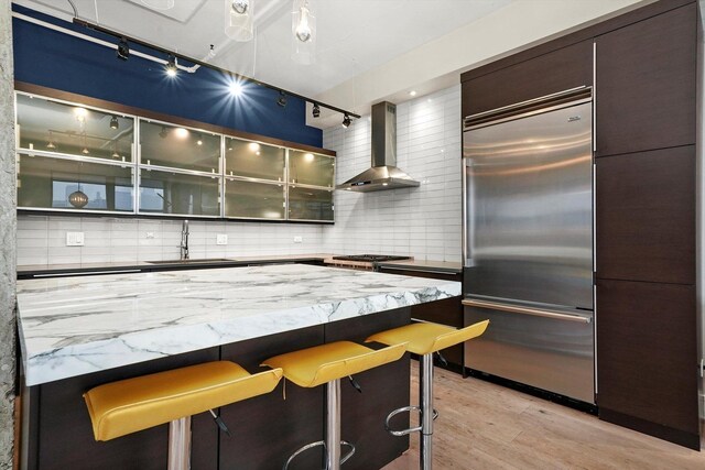 6 S Laflin St Unit 913, Chicago, IL 60607 - kitchen with built in refrigerator, wall chimney exhaust hood, a sink, light wood-style flooring, and a breakfast bar area