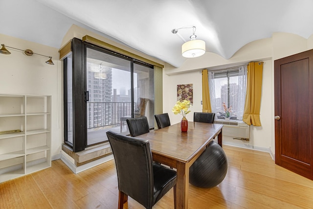 dining room featuring light wood finished floors, baseboards, and lofted ceiling