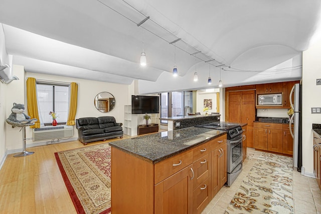 kitchen with appliances with stainless steel finishes, a kitchen island, open floor plan, dark stone counters, and healthy amount of natural light