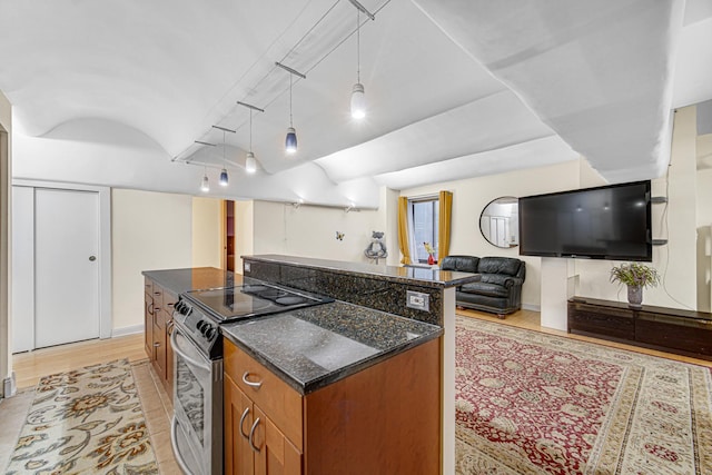 kitchen with electric stove, brown cabinetry, a kitchen island, open floor plan, and dark stone countertops
