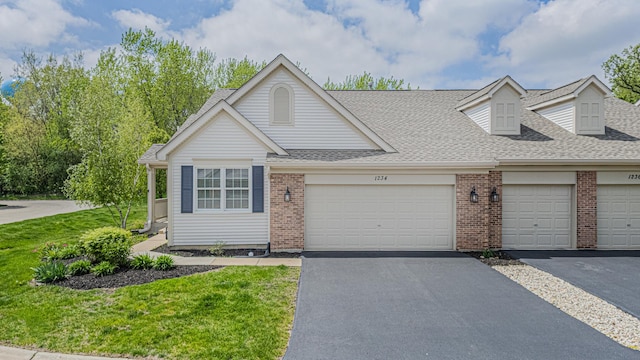 view of front facade with brick siding, a shingled roof, a front lawn, driveway, and an attached garage
